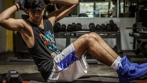 A young man performing sit-ups in a Manila gym, showcasing strength and fitness.